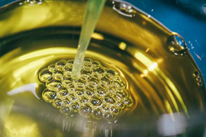 Un hilo de aceite cayendo sobre aceite dorado
